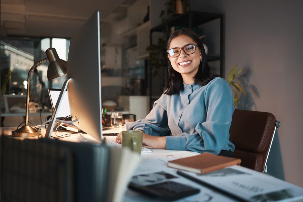 Business woman, computer and designer with smile for creative ambition, vision or goals at the office. Portrait of happy employee smiling in happiness for career in design or night shift at workplace